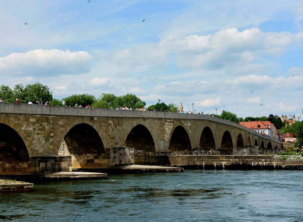 ALT-Text: Die Steinerne Brücke in Regensburg – das imposante mittelalterliche Bauwerk über die Donau, erbaut im 12. Jahrhundert, bietet einen atemberaubenden Blick auf die Altstadt und zählt zum UNESCO-Welterbe.